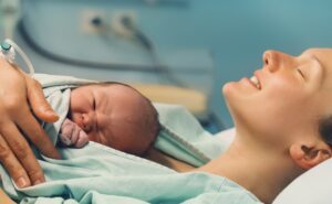 אישה לאחר לידה עם התינוק עליה