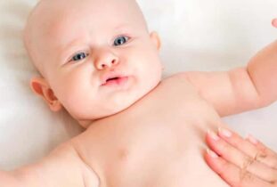 תינוקת שוכבת על הגב ועושים לה מסאג' בבטן