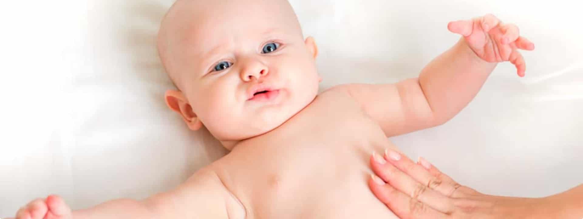 תינוקת שוכבת על הגב ועושים לה מסאג' בבטן