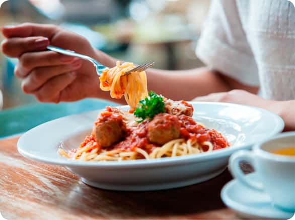 אישה אוכלת פסטה עם כדורי בשר