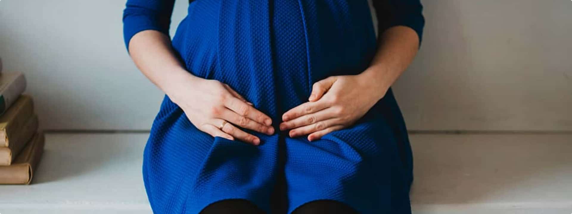 אישה בהריון יושבת ומחזיקה את הבטן