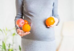 אישה בהריון מחזיקה תפוזים