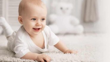 תינוקת שוכבת על הבטן ומחייכת